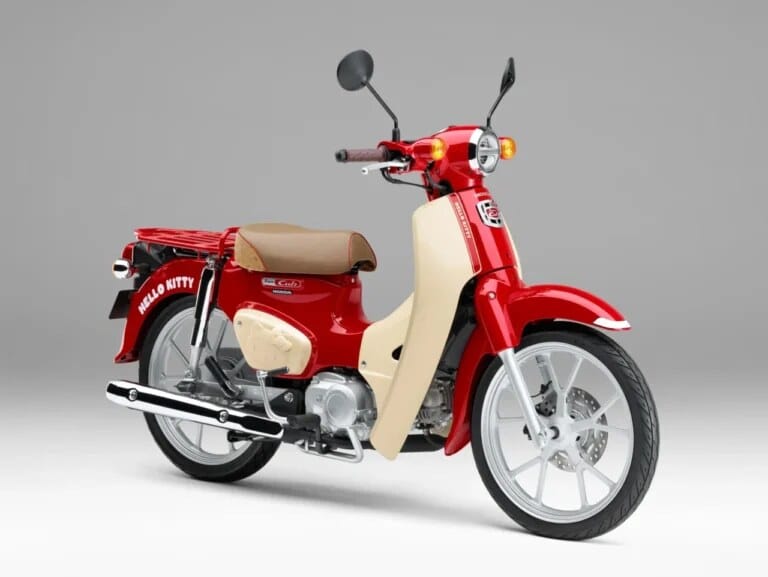 Tampak samping Honda Super Cub edisi Hello Kitty dengan warna bodi lembut dan detail emblem khusus